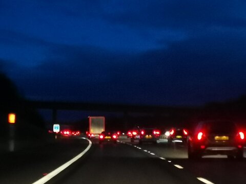 Defocused rear car lights on motorway with dark blue sky above.