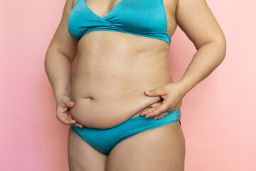Pinch woman sagging belly with fingers closeup, folds on stomach, loose skin and cellulite. Naked...