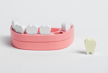 Wooden jaw model and fallen out bad tooth with plaque, cavity. Teeth diseases, inflammation, poor oral hygiene concept. Children game at dentist. High quality photo