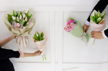 Spring flowers bouquets. Couple man and woman hands holding white and pink tulips and hyacinths...