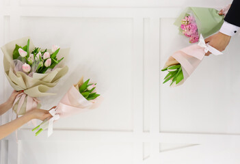 Spring flowers bouquets. Couple man and woman hands holding white and pink tulips and hyacinths mono bouquets.