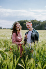 Young couple, guy and a girl are standing in a field and laughing
