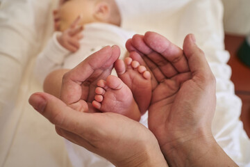 small legs of a newborn baby in female palms. love, motherhood, care