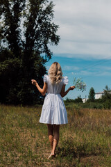 Obraz premium A girl in a rustic dress turned her back and holds flowers in her hand