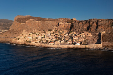 Fototapeta na wymiar Aerial view of ancient city Monemvasia behind fortress wall on shore of island at sunrise, Greece