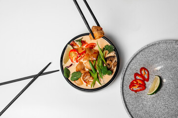 Ramen, soup with noodles and egg, with chopsticks. In a black round plate, ramen with chicken and mussels Asian cuisine.