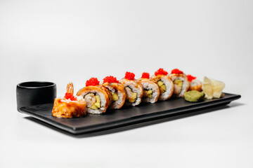 Sushi, rolls. Chinese and Asian cuisine, sets of rolls of ginger and soy sauce lie on a black board with chopsticks. Sushi is made in sets