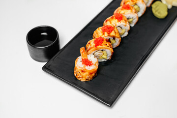 Sushi, rolls. Chinese and Asian cuisine, sets of rolls of ginger and soy sauce lie on a black board with chopsticks. Sushi is made in sets