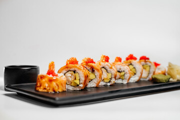 Sushi, rolls. Chinese and Asian cuisine, sets of rolls of ginger and soy sauce lie on a black board with chopsticks. Sushi is made in sets