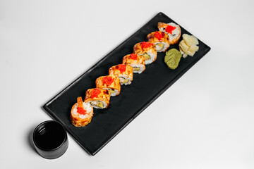 Sushi, rolls. Chinese and Asian cuisine, sets of rolls of ginger and soy sauce lie on a black board with chopsticks. Sushi is made in sets