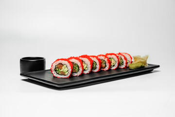 Sushi, rolls. Chinese and Asian cuisine, sets of rolls of ginger and soy sauce lie on a black board with chopsticks. Sushi is made in sets