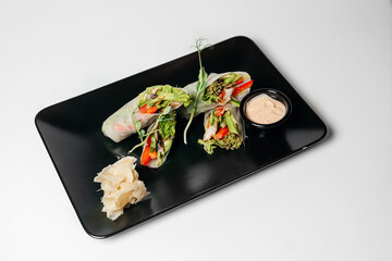 fresh vegetarian rolls with vegetables on a black plate beautifully laid out. Asian cuisine