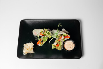 fresh vegetarian rolls with vegetables on a black plate beautifully laid out. Asian cuisine