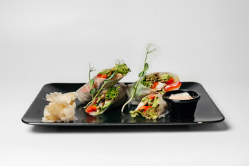 fresh vegetarian rolls with vegetables on a black plate beautifully laid out. Asian cuisine