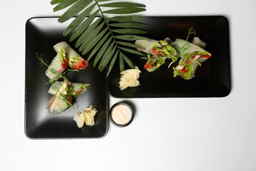 fresh vegetarian rolls with vegetables on a black plate beautifully laid out. Asian cuisine