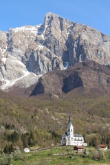 Beautiful church and village in front of the mountains with snows - the Alps in Slovenia