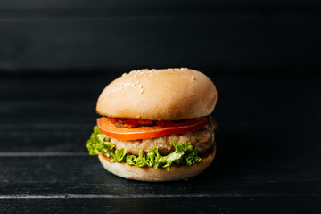 Tasty hot fresh hamburger on black wooden background composition