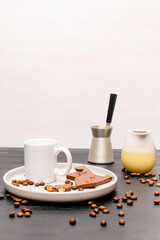 white espresso cup, mug, chocolate, coffee beans on plate kitchen table, utensils dishware, coffee pot on black wooden shelf. Early morning french home hot beverage breakfast, copy space