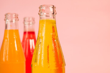 Some colorful cold soda bottles on pink background 