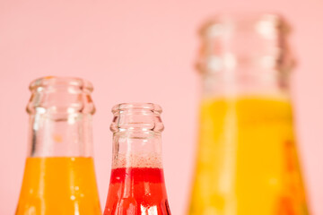 Some colorful cold soda bottles on pink background 
