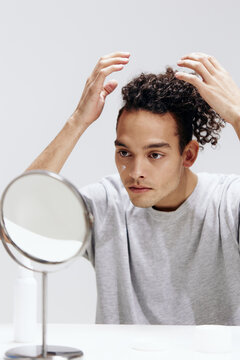 portrait of a man in a white T-shirt in front of a mirror skin care isolated background