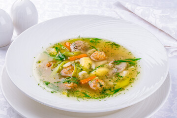 Chicken soup bouillon in a plate with chicken balls and vegetables