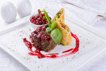 Venison steak with lingonberry sauce on a white plate
