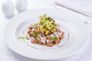 Salad with boiled veal and vegetables on a white plate - obrazy, fototapety, plakaty