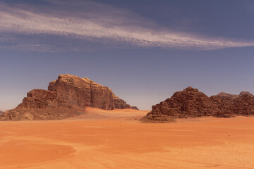 Widok pustyni Wadi Rum w Jordanii z skalistymi wzgórzami z czerwonego piaskowca i z błękitnym niebem. - obrazy, fototapety, plakaty