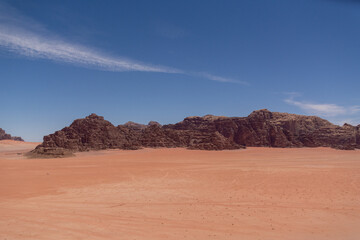 Widok pustyni Wadi Rum w Jordanii z skalistymi wzgórzami z czerwonego piaskowca i z błękitnym niebem.
