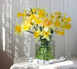 yellow daffodils on a table with lace indoors.