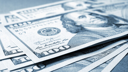 American paper money. Several one hundred dollar bills lie on textured surface. Focus on the number 100. Savings economy and the US dollar. Public debt and budget. Gray blue tinted illustration