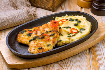 Chicken cutlets with mashed potatoes on black iron pan