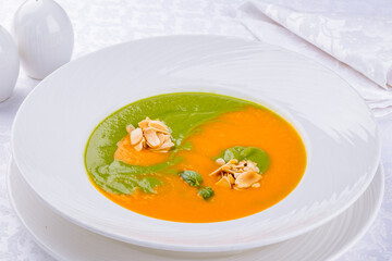 Soup cream of pumpkin with spinach on a white plate
