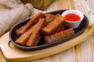 fried croutons with sweet chili sauce on cast iron pan