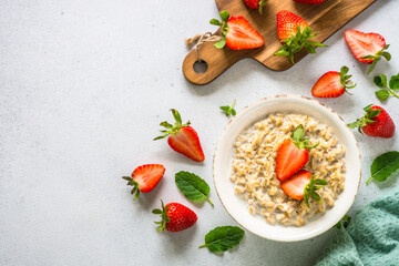 Oatmeal porridge with strawberry on white stone background. Top view with space for text.