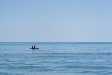 personas encima de una tabla de surf remando por la playa en el mar de oropesa españa