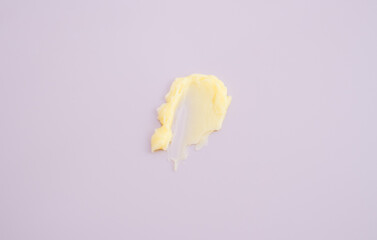 Cosmetic products creamy yellow stain texture on pink background. Texture of natural cosmetics, hair mask, cream, scrub