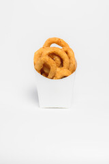 Rings of fried onions in batter lie in a box on a white background