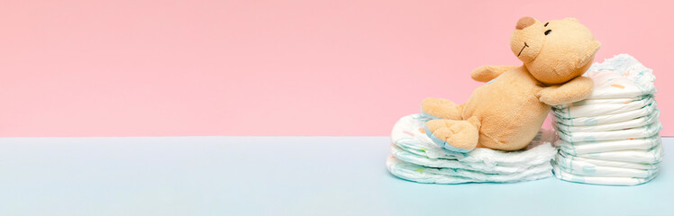 Stack of diapers with cute teddy bear toy lying on table. set for infant newborn boy girl for baby...