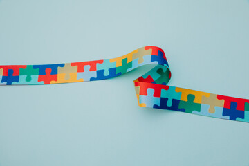 World Autism awareness and pride day with Puzzle pattern ribbon close-up on blue background
