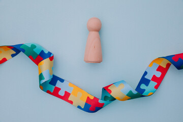 World Autism awareness day with puzzle pattern ribbon and wooden model as a symbol of person