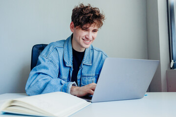 Smiling young man working on his laptop. Freelancer in the office or at home working.