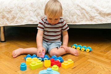 Cute little adorable caucasian boy playing with multi-colored constructor at home. Babys hands building tower of plastic blocks. Children logic development and childhood daycare, kindergarten concept