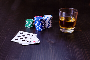 Closeup view of a poker hand with chips and a drink