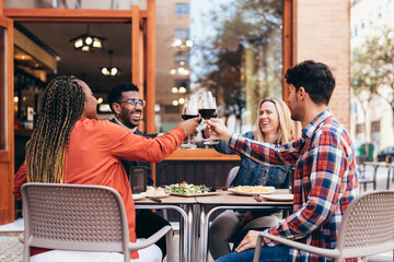 interracial gathering of friends toasting with red wine