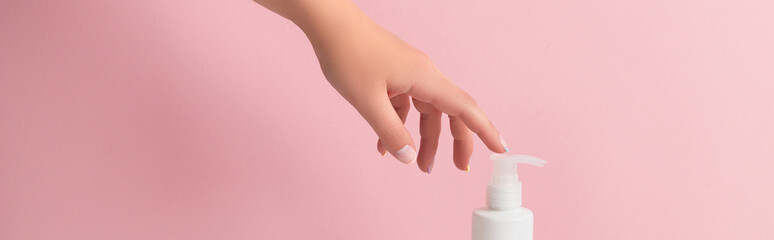 Groomed womans hand touch bottle of lotion or cream