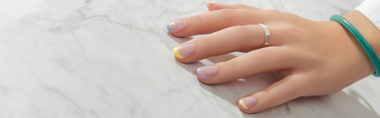 Beautiful womans hand with spring summer nail design on marble gray background