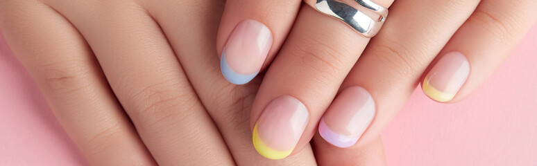 Close up manicured womans hands on pink background
