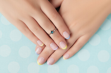 Beautiful womans hands with spring summer nail design on blue background